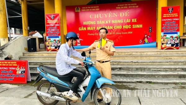 Cán bộ CSGT truyền đạt lý thuyết về kỹ năng lái xe gắn máy an toàn cho các em học sinh.