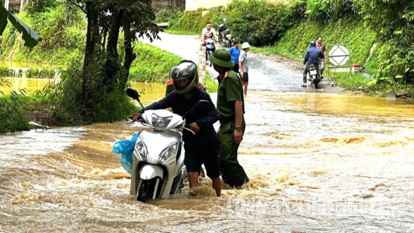 Công an xã giúp đỡ người dân di chuyển qua đập tràn.