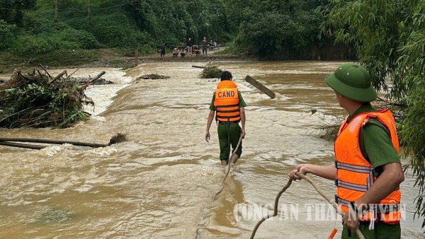 Công an xã Tân Kỳ đặt biển cảnh báo nguy hiểm và hỗ trợ người dân qua vùng nước ngập.