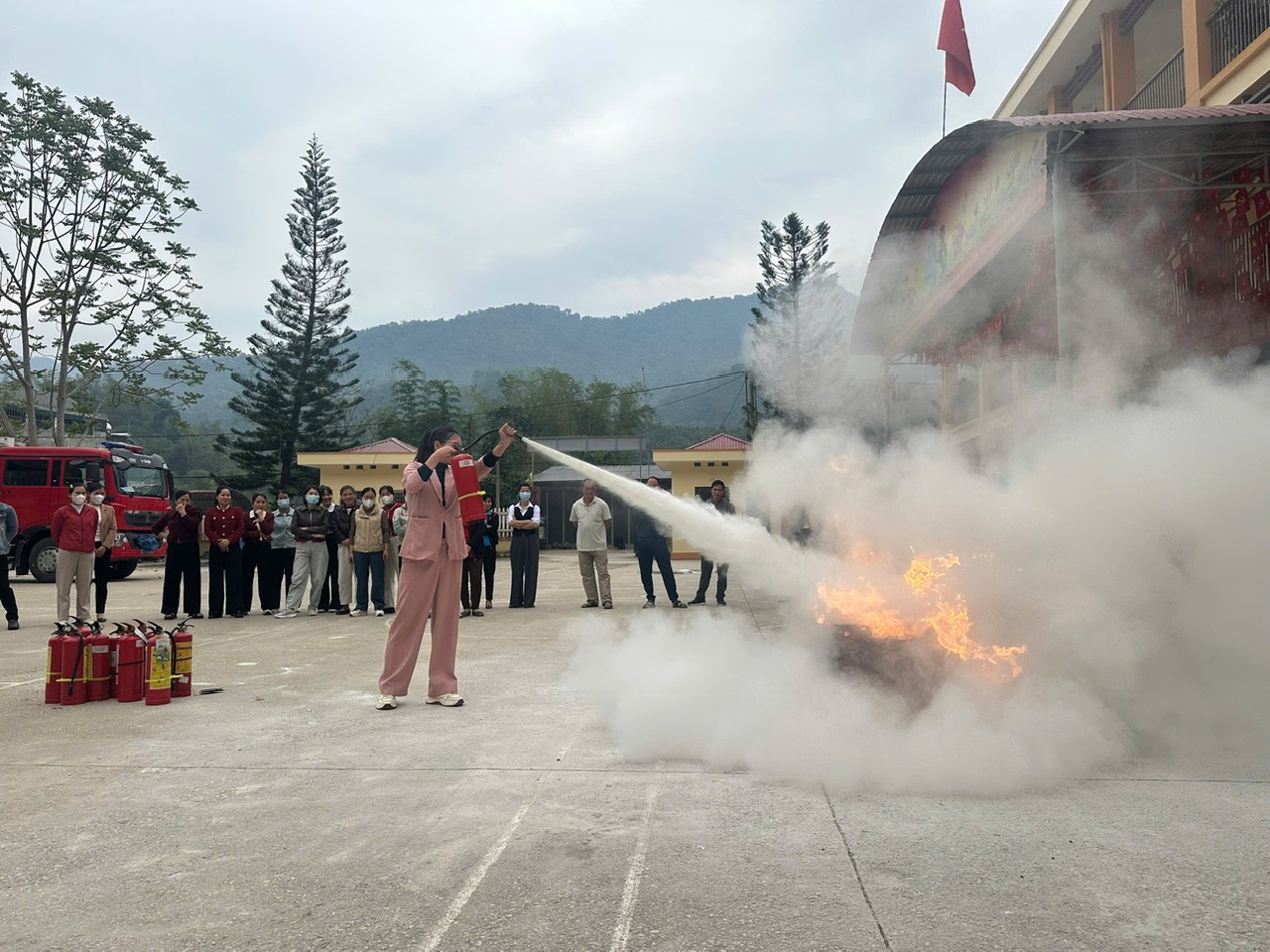 1 Cán bộ, giáo viên, nhân viên nhà trường thực hành sử dụng bình chữa cháy xách tay dập tắt đám cháy giả định