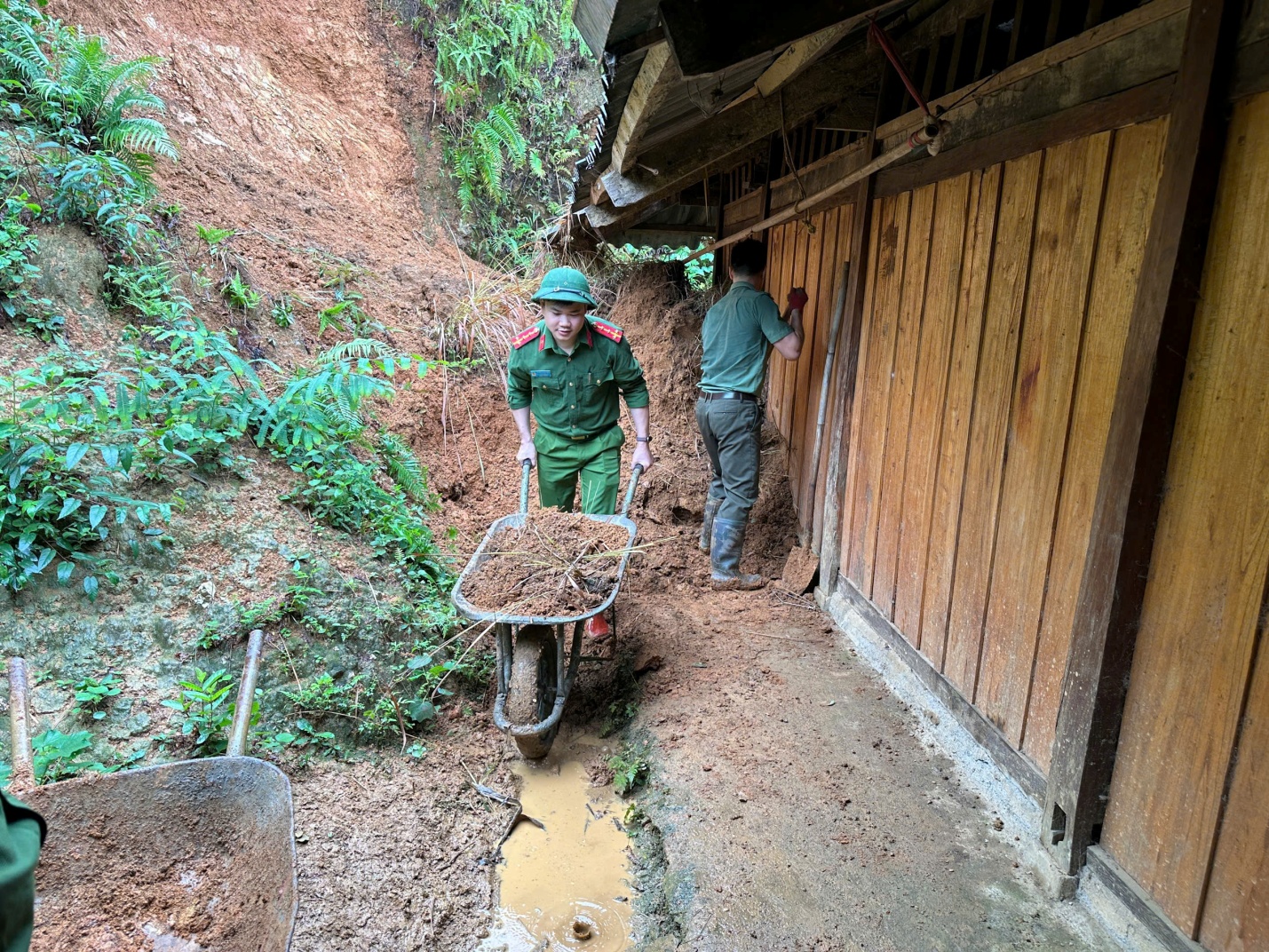 Cán bộ, chiến sĩ Công an xã Bằng Thành giúp người dân thu dọn đất tại khu vực nhà ở, khắc phục hậu quả thiên tai